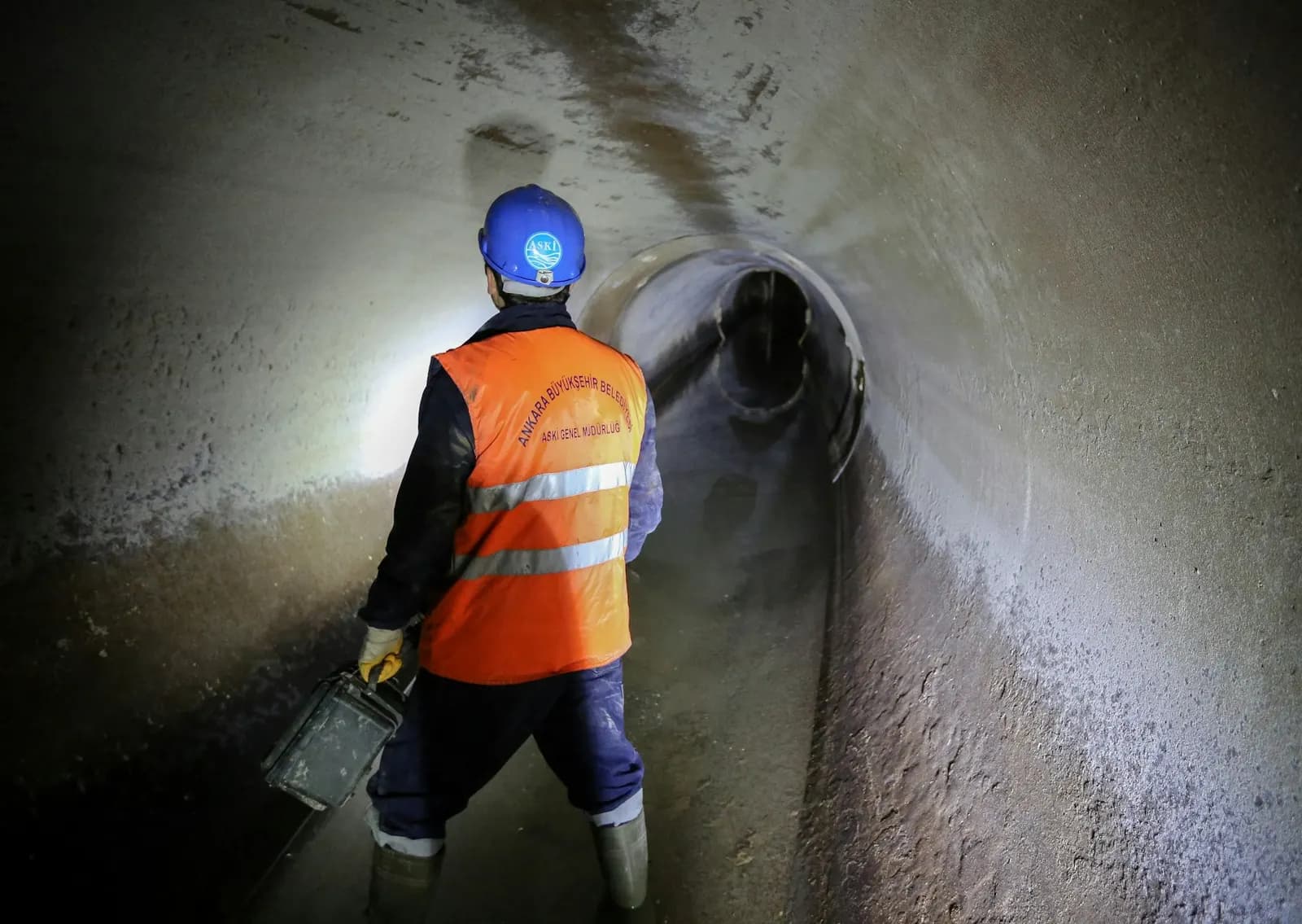 Engineer in hi-vis inspecting a sewer with a torch